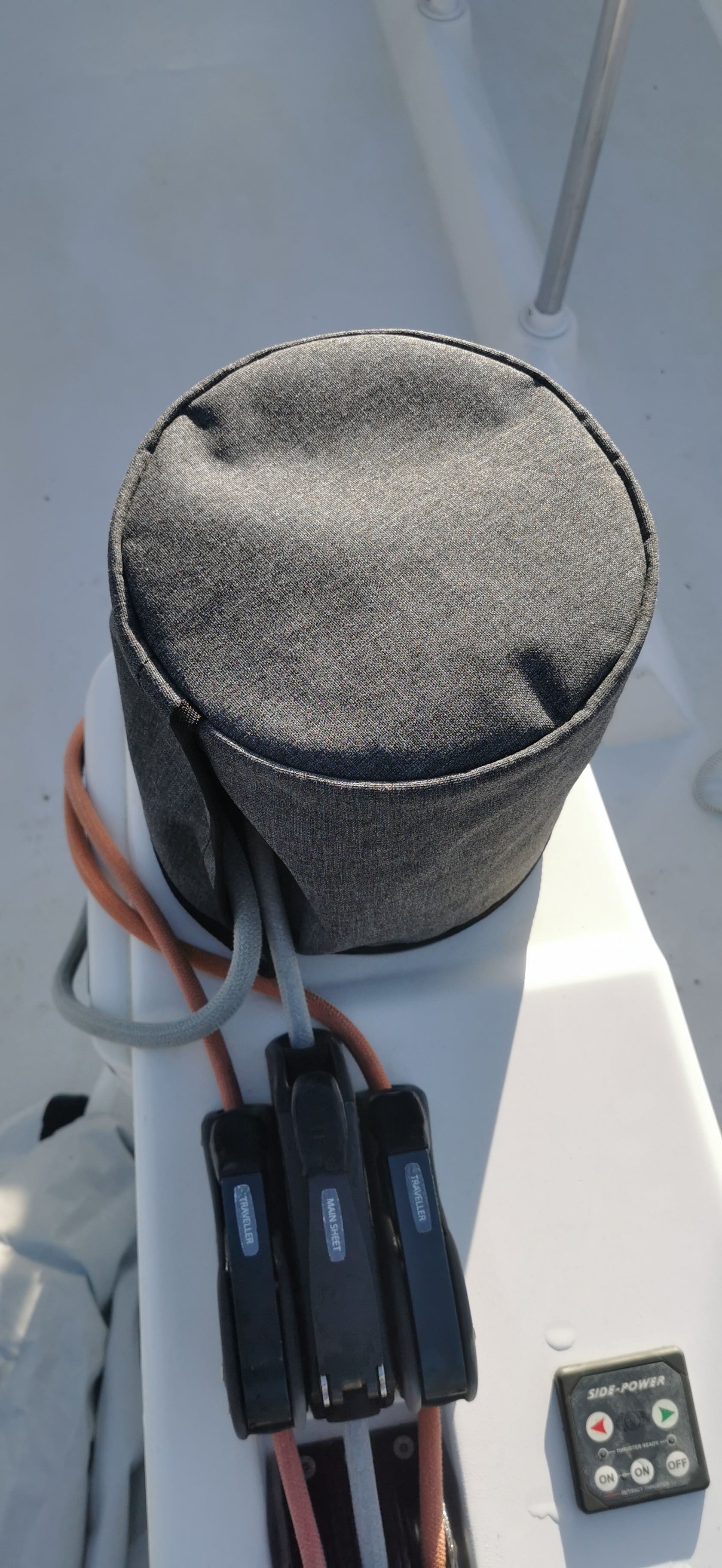 Gray winch cover on a boat with visible cables and control panel.